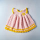 Baby-Strickkleid aus Baumwolle in Rosa mit gelben Details handgemacht Vorderseite mit Knopfverschluss und feiner Häkelstruktur